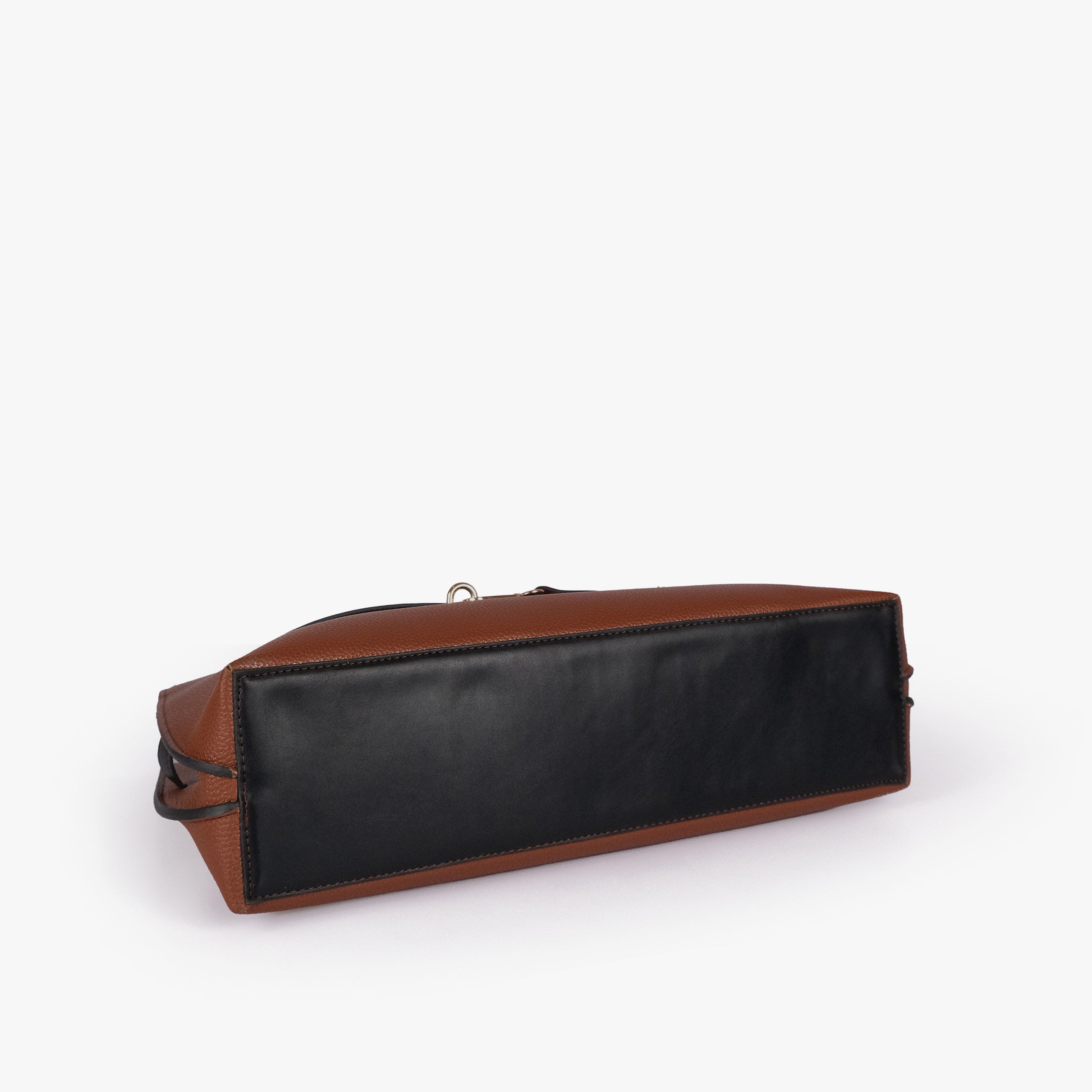 Brown cognac Monday Tote — underside tilted view showing reinforced black smooth base panel and cognac pebbled sides