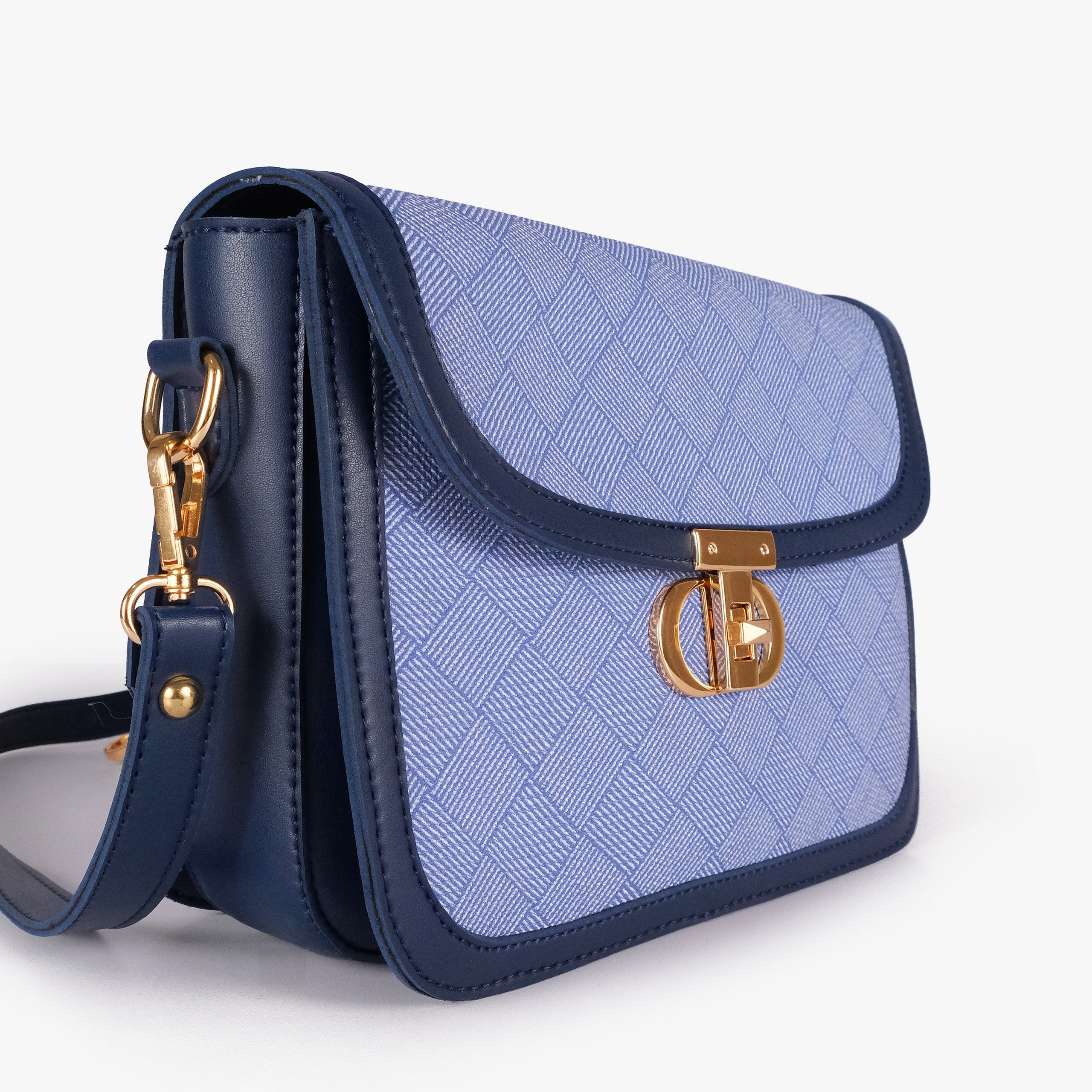 Navy contrast cross-body bag — closeup of periwinkle crosshatch box-texture panel, deep navy pebbled trim, and gold twist-lock rockstud
