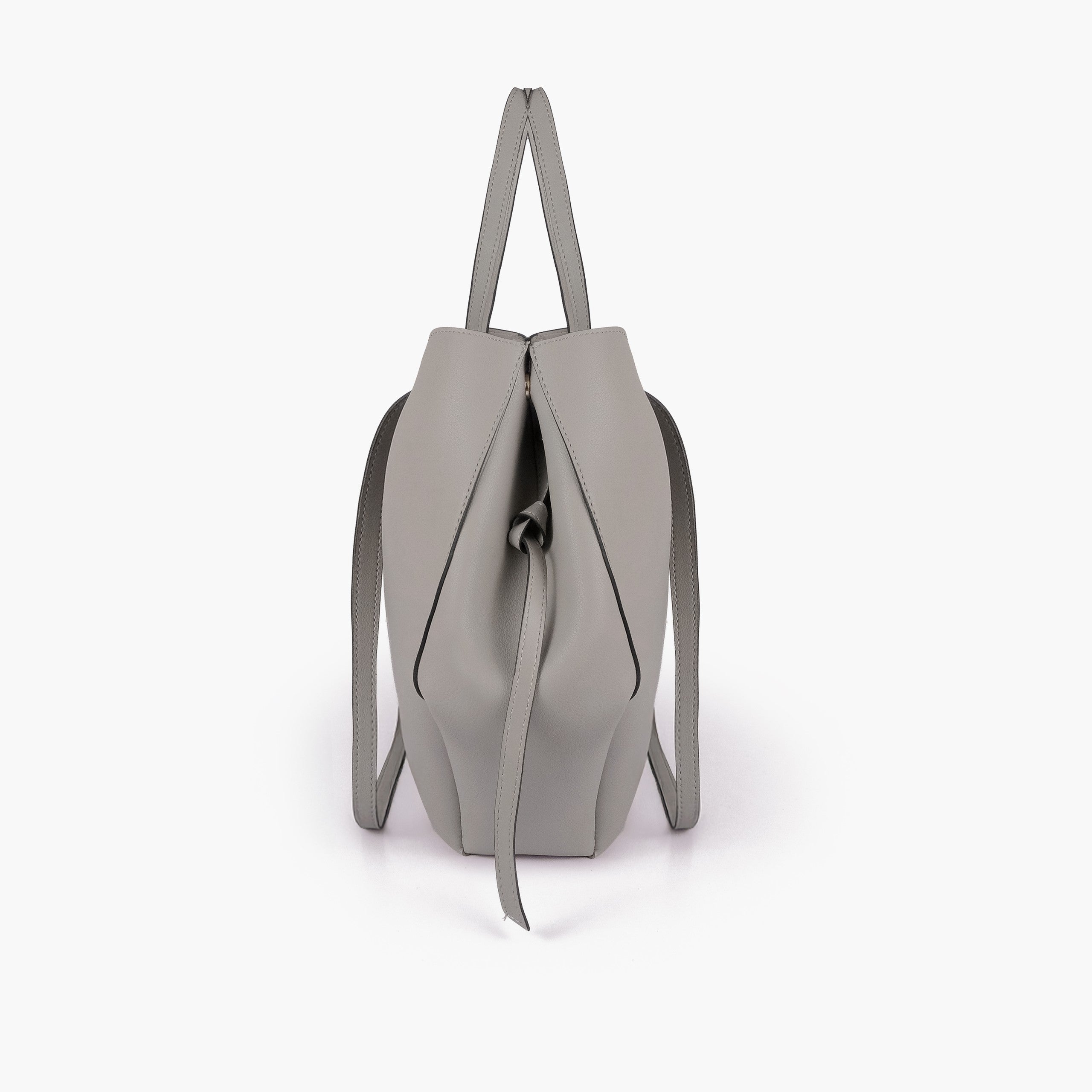 Grey atelier tote — side profile showing wing-cut origami fold, cinch tie, and slim shoulder handle
