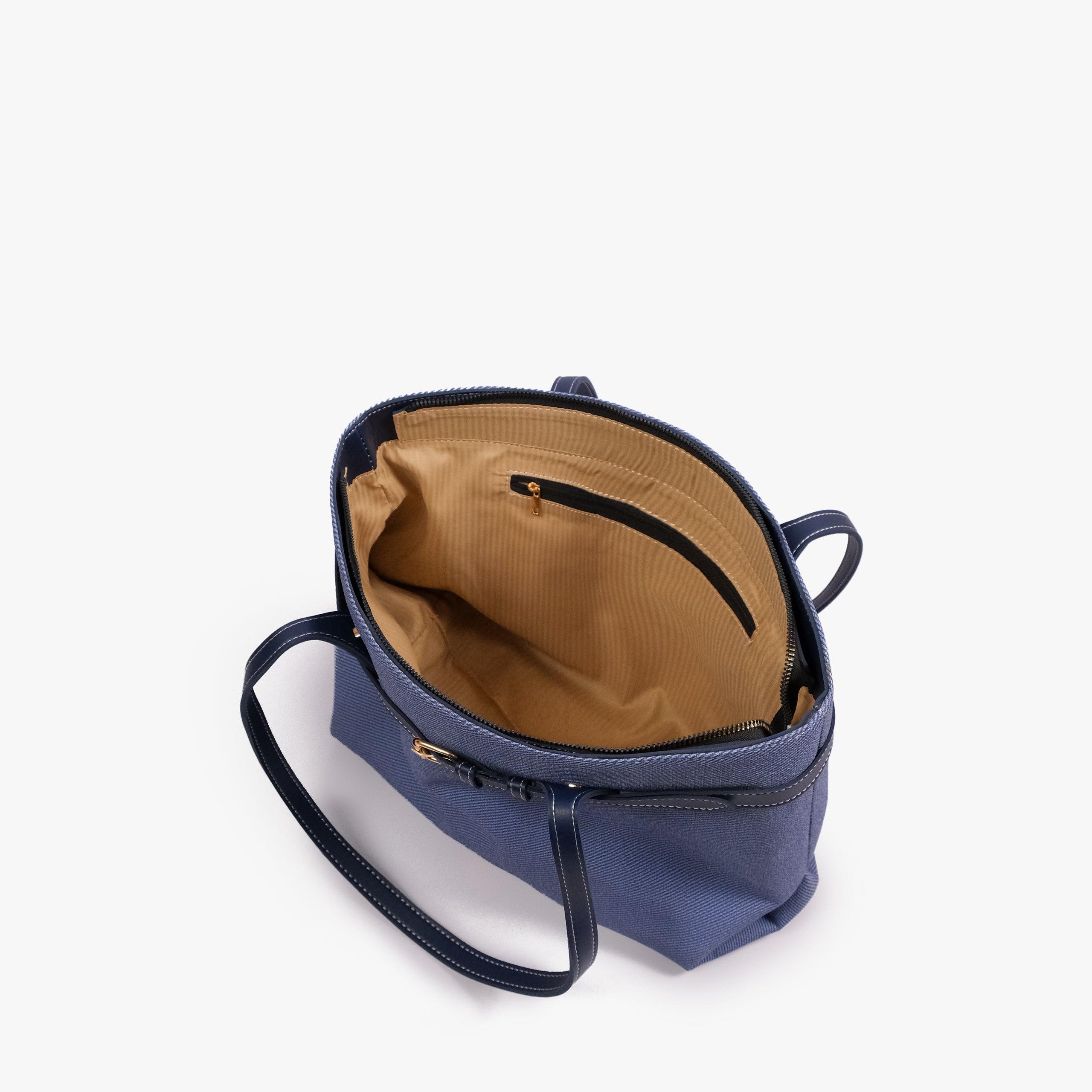 Navy belted tote bag — open-top interior view showing the tan interior, structured rim, long handles, and belted front detail, blue-navy textured body with dark smooth faux-leather trim