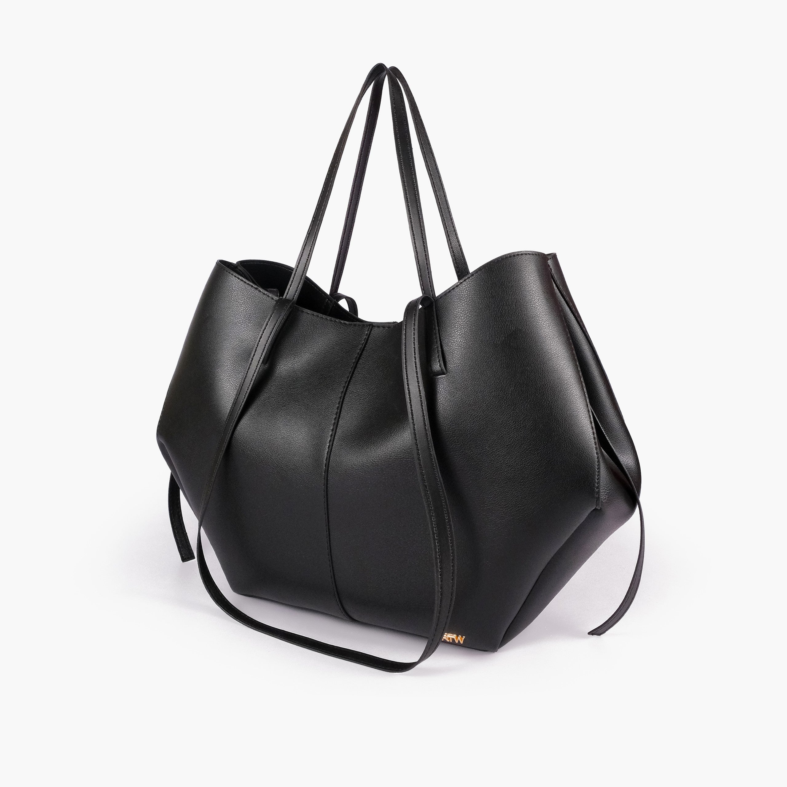 Black atelier tote — hero 3/4 quarter view, smooth matte faux leather, wing-cut origami side panels, slim shoulder handles, gold RTW logo at front base