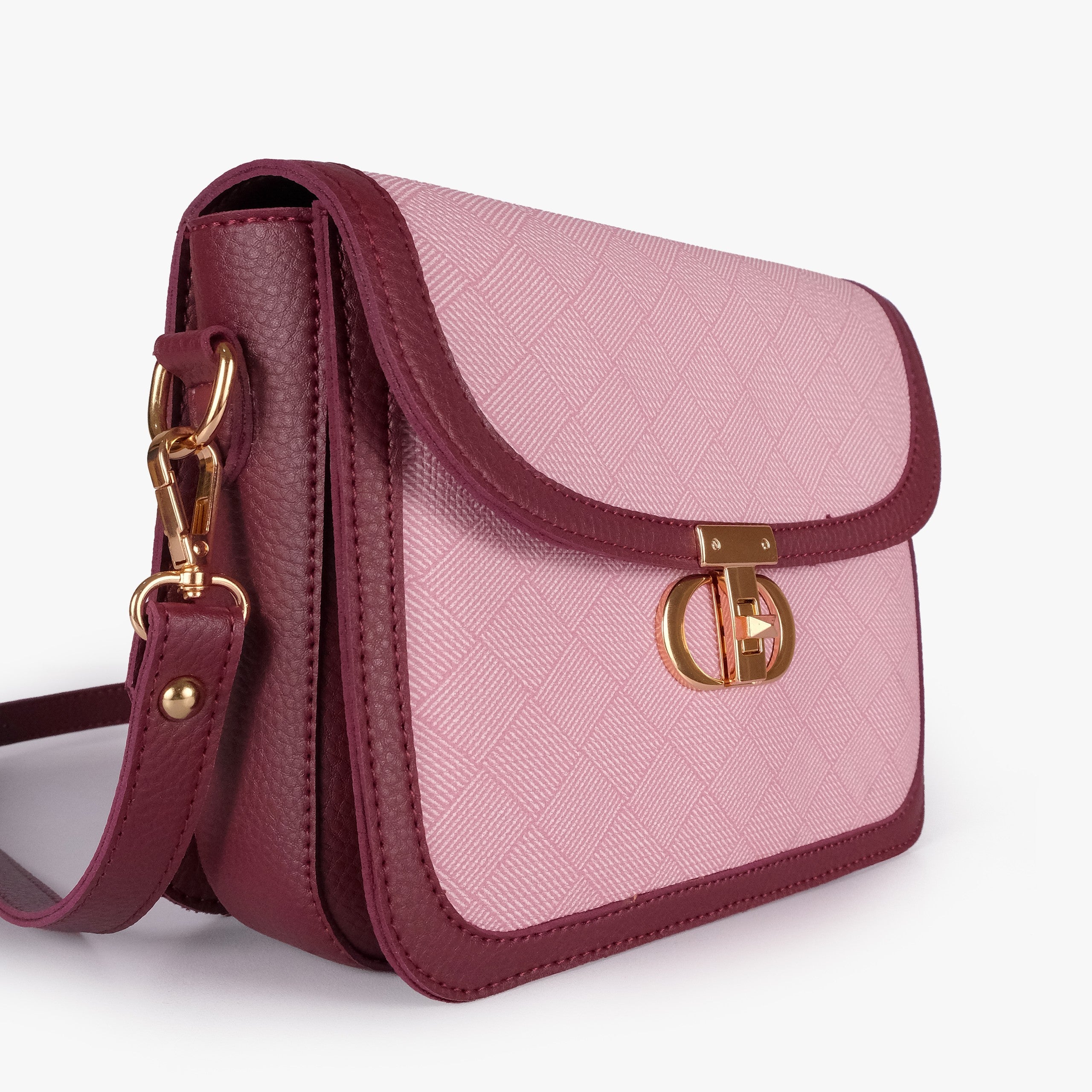 Pink contrast cross-body bag — closeup of soft pink crosshatch box-texture panel, deep burgundy pebbled trim, and gold twist-lock rockstud